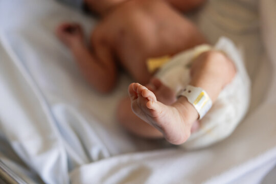 Newborn baby wearing hospital identification tag on foot
