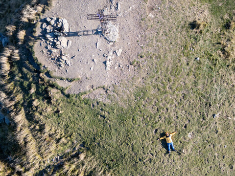 Aerial view of a person lying on the grass near a metal cross in Parco Nazionale dell'Appennino Tosco-Emiliano, Provincia di Massa e Carrara, Italy.