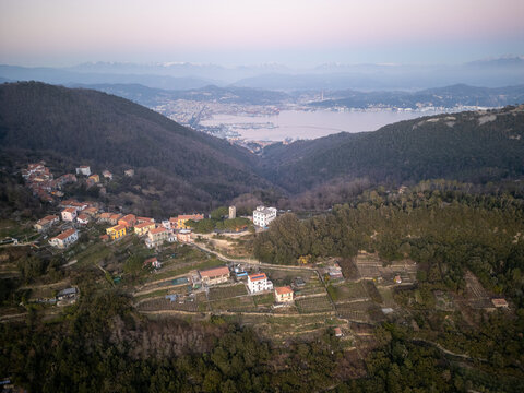 Aerial view of the Cinque Terre coastal landscape, featuring terraced hills, scattered houses, and the Gulf of La Spezia in the background, La Spezia, Liguria, Italy.