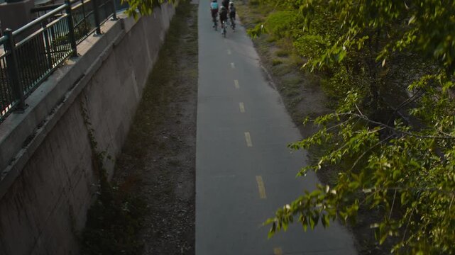 Group of cyclists biking down a path in denver shot from the top of a bridge