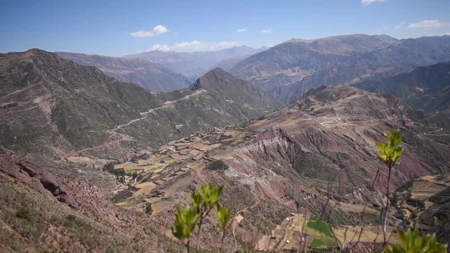Green shrubs framing a vast Andean mountain valley in Paruro, Cusco, Peru.