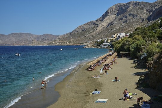 Massouri, people relaxing on sandy beach with mountains in the background and swimming in the clear sea, Kalymnos, Sponge Diving Island, Dodecanese, Greek Islands, Greece