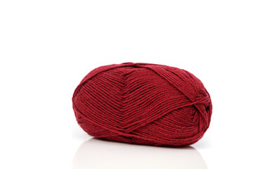 Beautiful deep red yarn ball resting elegantly on a smooth surface under soft lighting in a cozy...