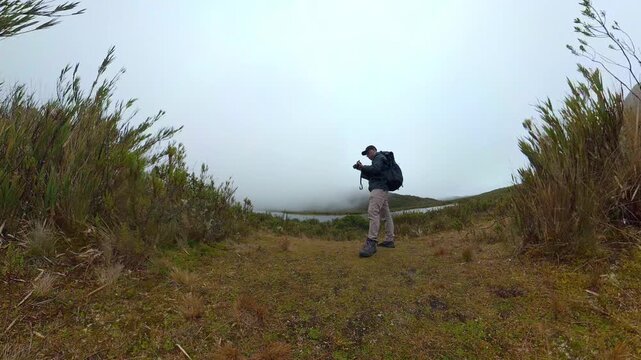 Hiker taking photos in a foggy paramo landscape