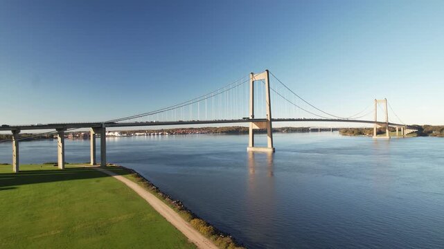 Aerial footage of the New Little Belt suspension bridge crossing calm blue water between Jutland and Funen near Middelfart and Fredericia, Denmark.