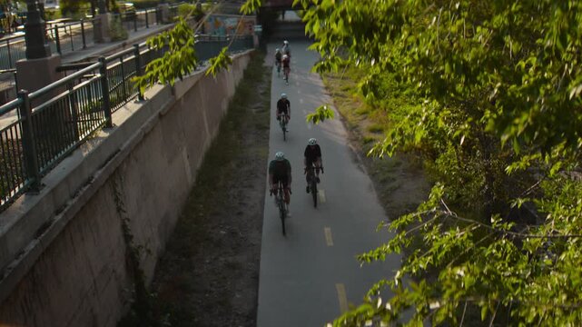 Group of cyclists biking down a path in denver shot from the top of a bridge