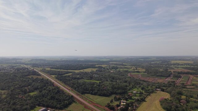 Avi&oacute;n surcando el cielo sobre paisaje verde y autopista, transporte y movilidad en entorno natural