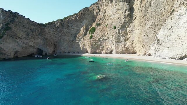 4K Aerial retreating shot of Chomi Beach with clear blue sea and towering cliffs near Paleokastritsa