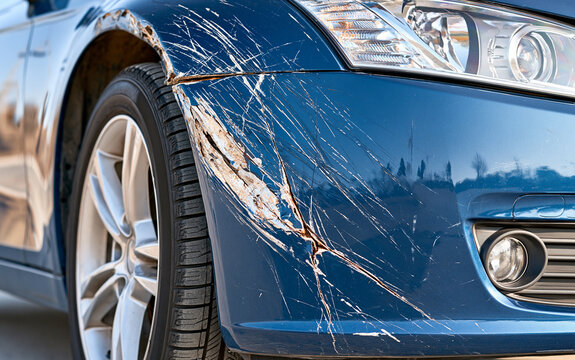 Close up of damaged blue car bumper with scratches and crack