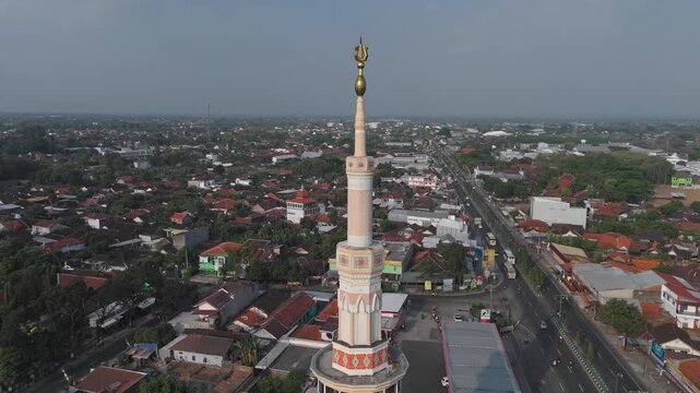 Aerial view of the Al Aqsha Great Mosque Klaten minaret rising above the surrounding urban landscape with rooftops and roads in Kecamatan Klaten Utara, Jawa Tengah, Indonesia.