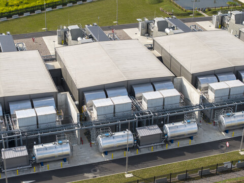 Aerial view of an AI data center power generator system featuring large metallic fuel tanks, industrial cooling units, and concrete structures in Poland.