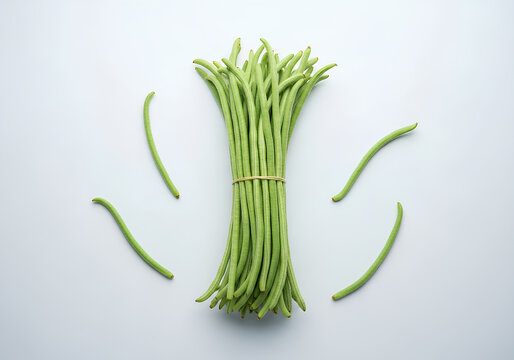 Top view of a bundle of fresh raw yardlong beans or kacang panjang tied together on a light grey surface.