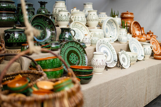 Handmade ceramic cups, bowls and vases displayed for sale at an outdoor craft market. Artisan pottery with unique glazes represents traditional craftsmanship and local small business.