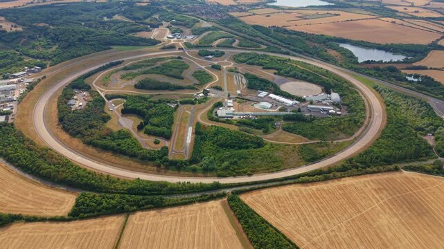 Aerial view of Millbrook Proving Ground featuring the circular test track surrounded by lush greenery and agricultural fields in Bedford, England, United Kingdom.