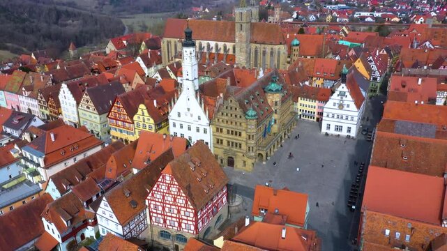 4K aerial view over Rothenburg ob der Tauber, Germany, showing the historic medieval old town, churches, city walls, traditional houses and red tiled rooftops.