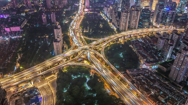 Aerial view of the illuminated Yan'an Elevated Road interchange with heavy traffic light trails winding through the dense urban skyline of Shanghai, Shanghai, China.