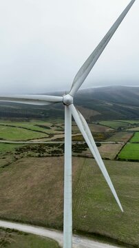 Aerial view of a wind turbine at Parque eolico Neda surrounded by green rural fields in Lugo, Lugo, Spain.