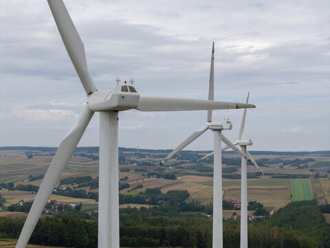 Aerial view of wind turbines overlooking vast agricultural fields and forests in Poland.