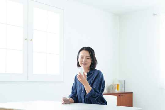 サプリメントをパッケージを確認する中高年女性