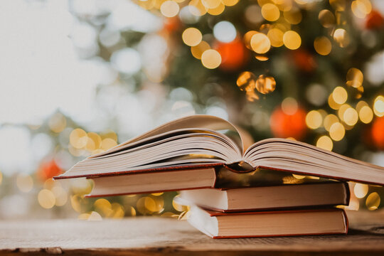Open Book on Stack With Christmas Bokeh Background.festive literary background for bookstore advertising, library events, winter reading challenges and holiday storytelling. 