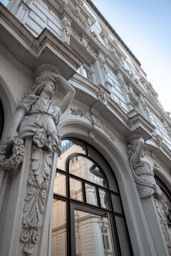 Hamburg, Germany - July 1, 2026: Low-angle architectural detail of an ornate historic building facade with sculpted female figures and decorative stonework in central Hamburg, Germany.