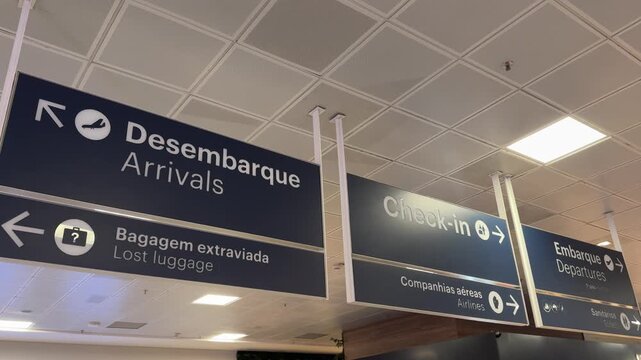 Directional airport signs for arrivals, check-in, airlines and lost luggage inside Vitória Airport, Brazil.