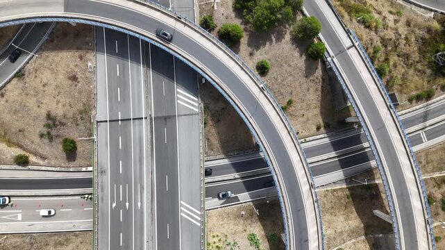 Aerial view of A5 highway interchange with cars driving on curved and straight roads through dry landscape in Cascais, Lisboa, Portugal.