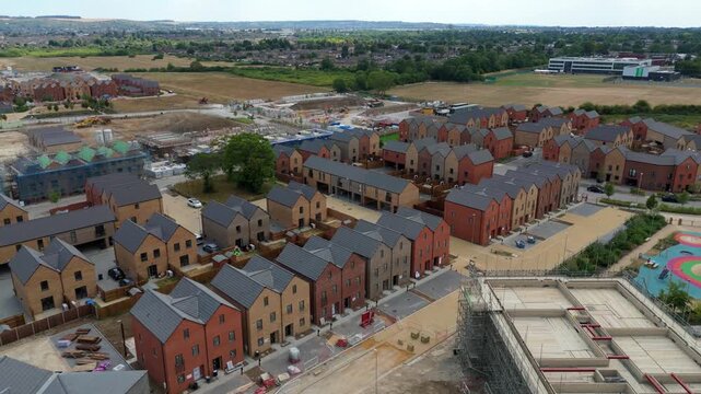 Aerial view of a modern residential housing development with red brick houses, paved streets, and ongoing construction work in Luton, England, United Kingdom.