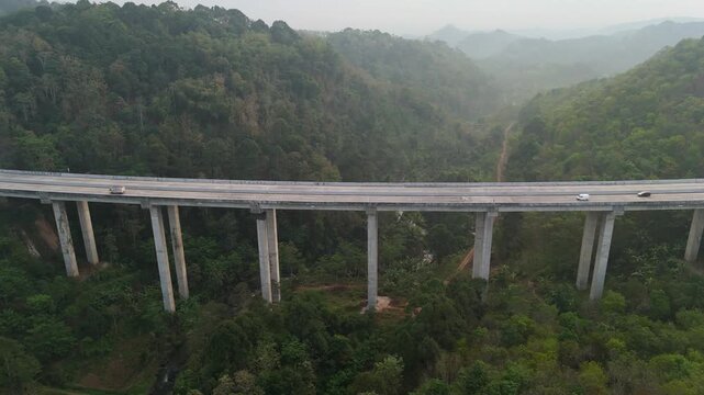 Aerial view of the Tuntang Bridge spanning across a lush green valley with concrete pillars and hilly forest landscape in Tuntang, Central Java, Indonesia.