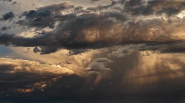 Aerial view of monsoonal clouds shifting from silver chrome and gold hues as dusk light ripples on the turbulent surfaces over Santa Fe, New Mexico, United States.