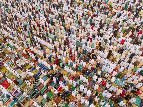 Aerial view of a large crowd of people performing Eid prayer in orderly rows on colorful prayer mats in Narayanganj, Dhaka, Bangladesh.