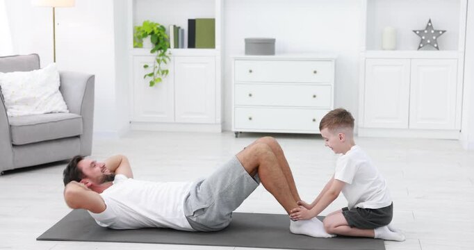 Boy helping his father to do exercise at home