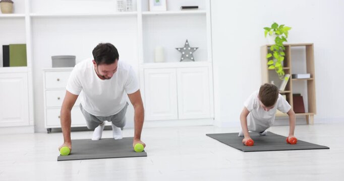 Father and his son exercising with dumbbells at home