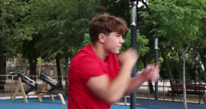 Teenage boy shadowboxing before workout at outdoor sports ground