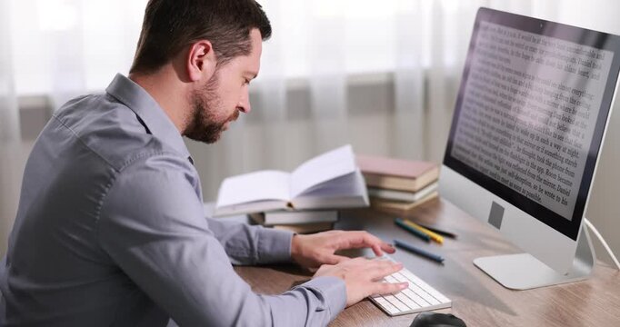 Author writing his book on computer at desk in office