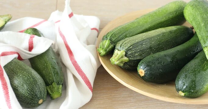 Many fresh raw zucchinis on wooden table, closeup. Camera moving right