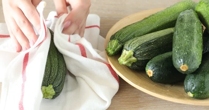 Woman with many fresh raw zucchinis at wooden table, closeup