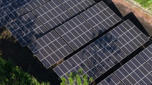 Aerial view of PLTS 1MWp Bangli solar panels arranged in rows with surrounding green vegetation in Bangli, Bali, Indonesia.