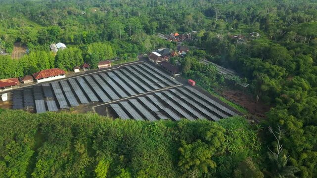 Aerial view of PLTS 1MWp Bangli solar power plant surrounded by lush tropical forest in Bangli, Bali, Indonesia.