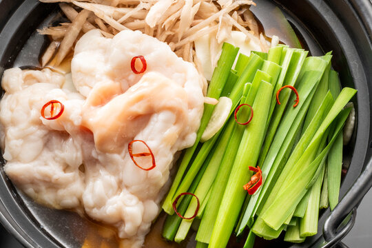 Motsu nabe Japanese hot pot with beef offal, scallions and red chili slices prepared in dark clay pot