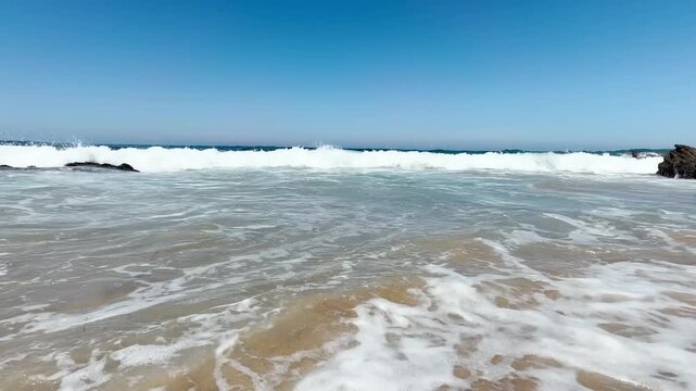 Waves on the beach on a hot summer day under a blue sky