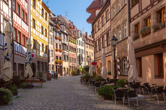 Cobblestone street lined with colorful historic buildings and outdoor cafes in Nuremberg, Germany.
