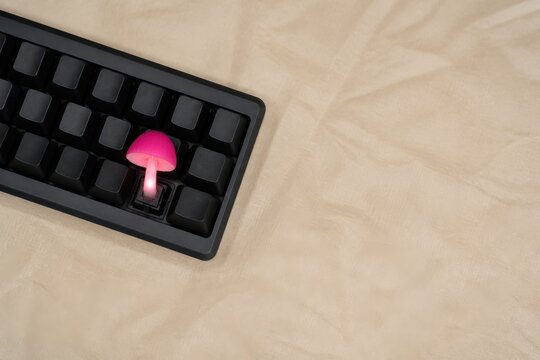 Pink glowing keycap on a keyboard with beige fabric copy space