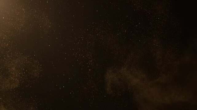 Glowing golden dust particles and glitter floating and scattering against a dark background
