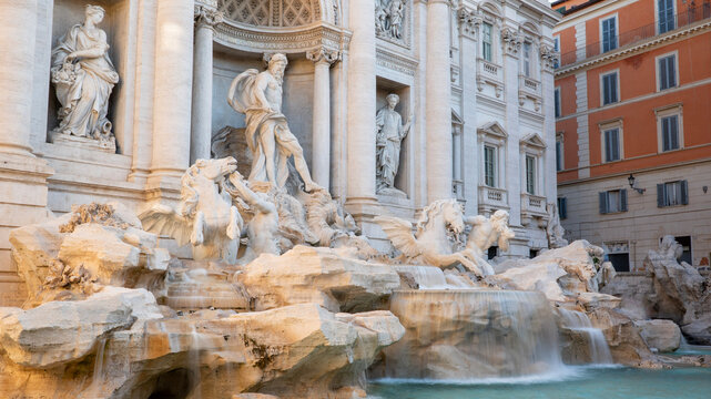 Water flows in the Trevi Fountain in the heart of Rome, Italy on a bright summer day