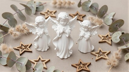 Naklejka premium Three white angel figurines surrounded by wooden stars and dried eucalyptus leaves.