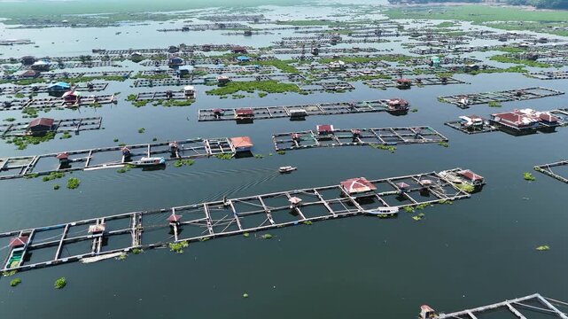 Aerial view of floating fish farms at Waduk Cirata with wooden structures and small boats on the water in Cianjur, West Java, Indonesia.