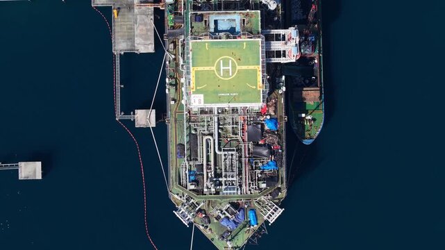 Aerial view of the Cinta Natomas floating storage and offloading ship moored in the deep blue sea, showing industrial deck equipment and piping in Buleleng Regency, Bali, Indonesia.