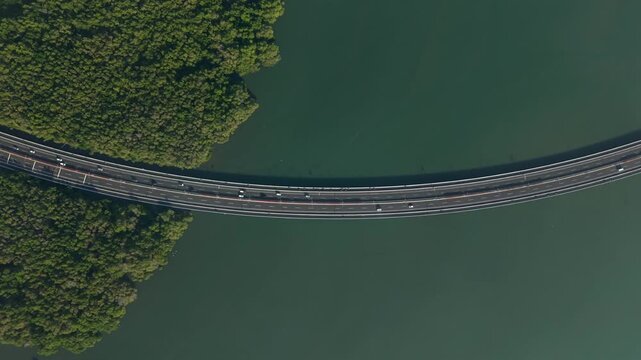 Aerial view of Bali Mandara Toll Road crossing the water with lush mangroves in Kecamatan Kuta Selatan, Bali, Indonesia.