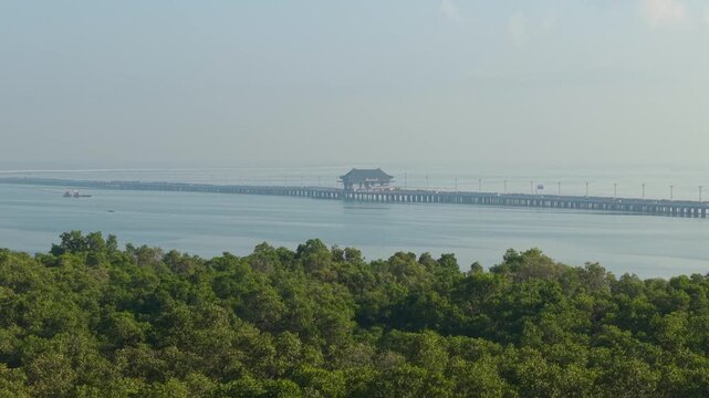 Aerial view of the Bali Mandara Toll Road stretching across the sea with lush mangrove forests in the foreground in Kecamatan Kuta Selatan, Bali, Indonesia.